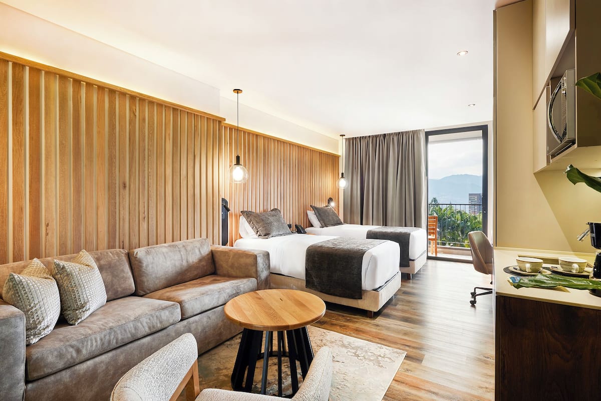Una habitación de hotel moderna con un sofá, una mesa redonda de madera, una cama y un escritorio con una silla.
