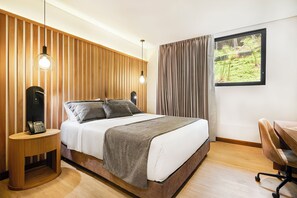 Ein modernes Schlafzimmer mit einer Wand aus Holzlatten, einem Bett mit weißer und grauer Bettdecke, einem Nachttisch mit Lampe und einem Fenster mit Vorhängen.