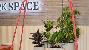 Un interno moderno con un cartello che indica 'WORK SPACE', piante in vaso e una scultura astratta rossa.