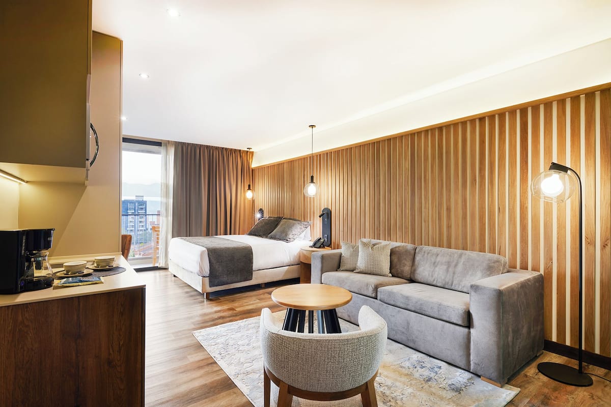 Una habitación de hotel moderna con cama, sofá, escritorio y vistas a la ciudad.
