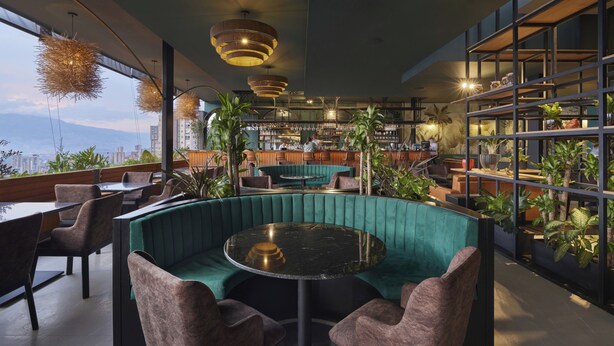 Un moderno bar con asientos, vistas de la ciudad y plantas de interior.