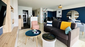 A modern living room with a sofa, coffee table, and a round side table. There is a kitchen area in the background.