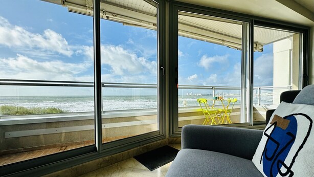 A modern room with large windows offering a view of the ocean and city skyline.
