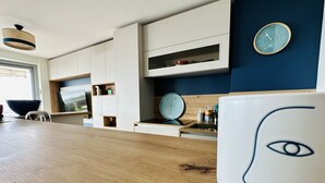 A modern kitchen with white cabinetry, a wooden countertop, and a wall-mounted clock.