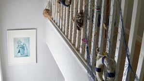 Een trap met een witte leuning, een vangnet en diverse decoratieve elementen, waaronder een reddingsboei en een ingelijste foto aan de muur.