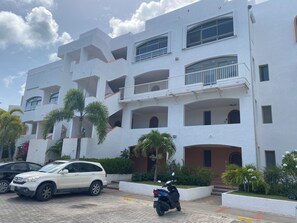 Un immeuble à plusieurs étages doté de balcons, d’une façade blanche et d’une allée pavée.