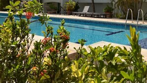 A hotel with a swimming pool, palm trees, and a clear blue sky. - Simpsonbay Yachtclub apartment with pool (Cole Bay)