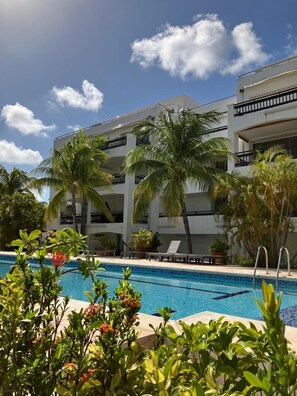 Ein Hotel mit Swimmingpool, Palmen und blauem Himmel.