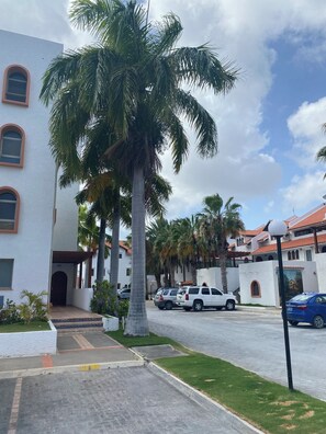 A residential area with a white building, palm trees, parked cars, and a clear sky. - Simpsonbay Yachtclub apartment with pool (Cole Bay)