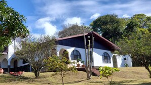 A white building with arched windows and a red roof, surrounded by trees and grass. - Romantic Rustic Villa in the Mountains 30 Minutes from The  airport . (Barva)