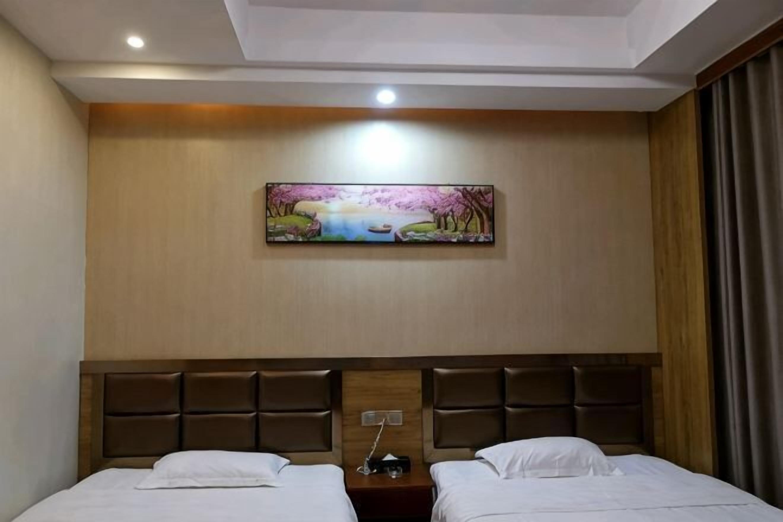 A hotel room with two beds, a headboard with a wooden panel design, a painting on the wall, and a nightstand with a lamp.