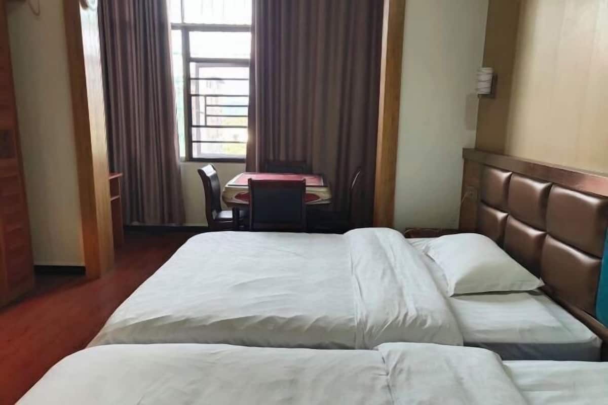 Una habitación de hotel con dos camas, una mesa de comedor y una silla.