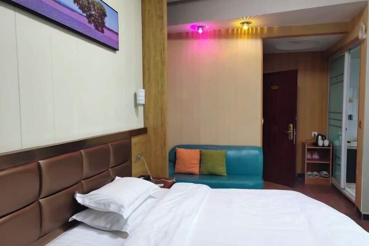 Una habitación de hotel con una cama, un sofá azul y un armario de madera.