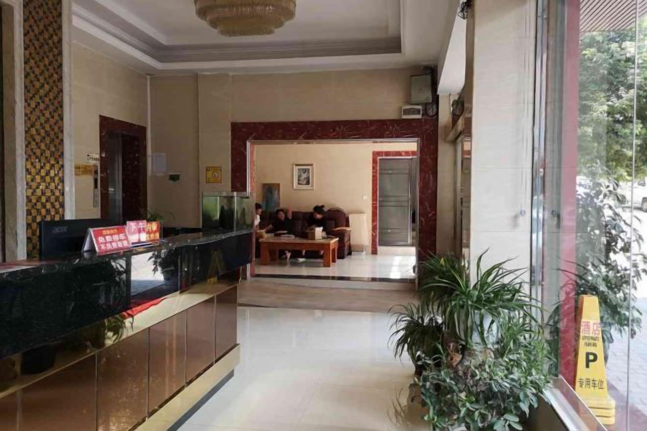 A hotel lobby with a reception desk, seating area, and a large window.