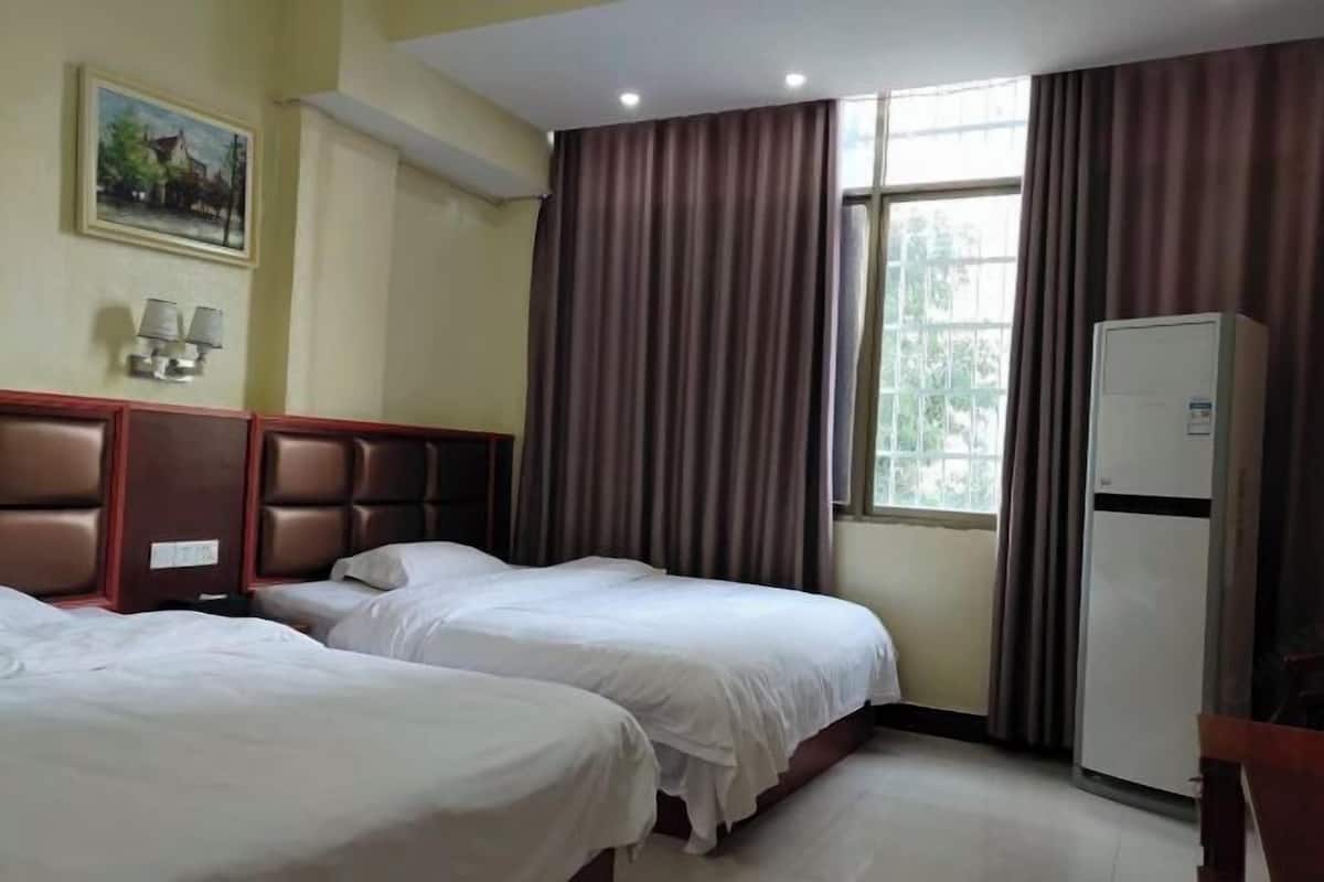 Habitación de hotel con dos camas, un cuadro en la pared, una ventana con cortinas y un refrigerador.