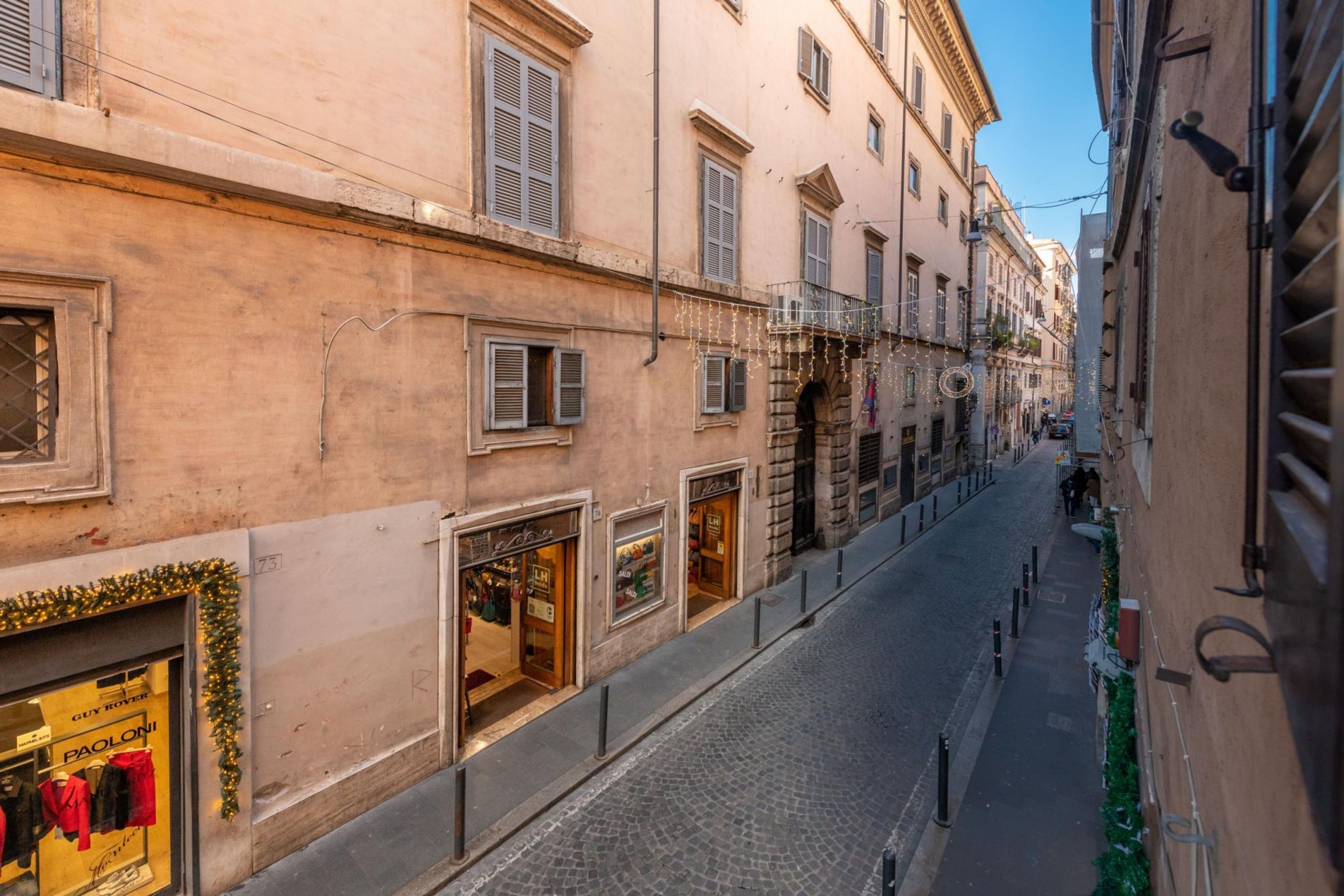 A narrow cobblestone street lined with buildings, some with storefronts and others with residential entrances.