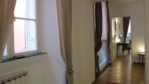A hallway with a radiator, a dining area with a table and chairs, and a view of the outside through a window. - Banchi Nuovi - Castel Sant Angelo (Rome)