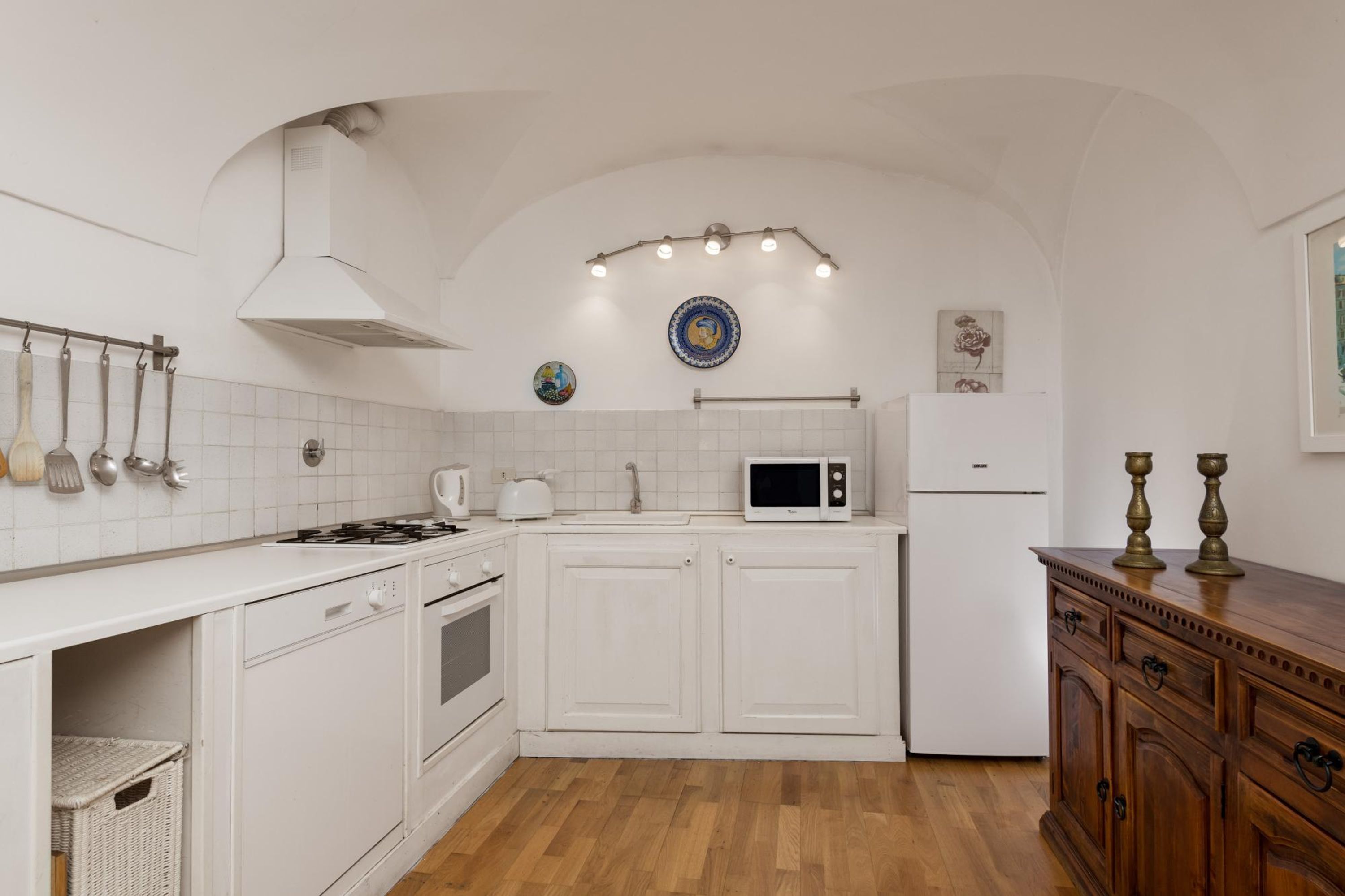 A compact kitchen with white cabinetry, a microwave, a stove, and a sink.