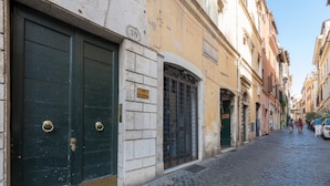 A cobblestone street with historic buildings, a green double door, and a metal gate. - Banchi Nuovi - Castel Sant Angelo (Rome)