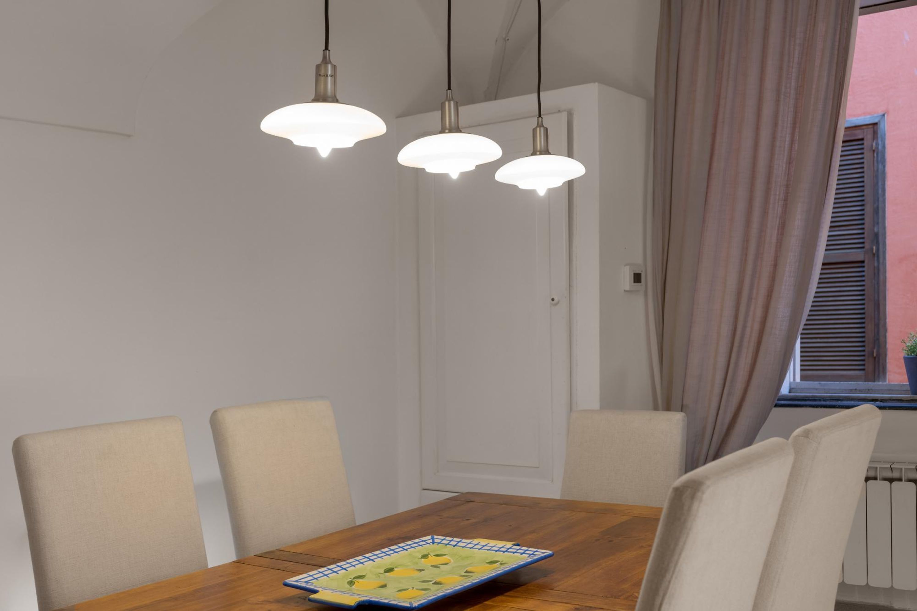 A dining area with a wooden table, four chairs, and three pendant lights.