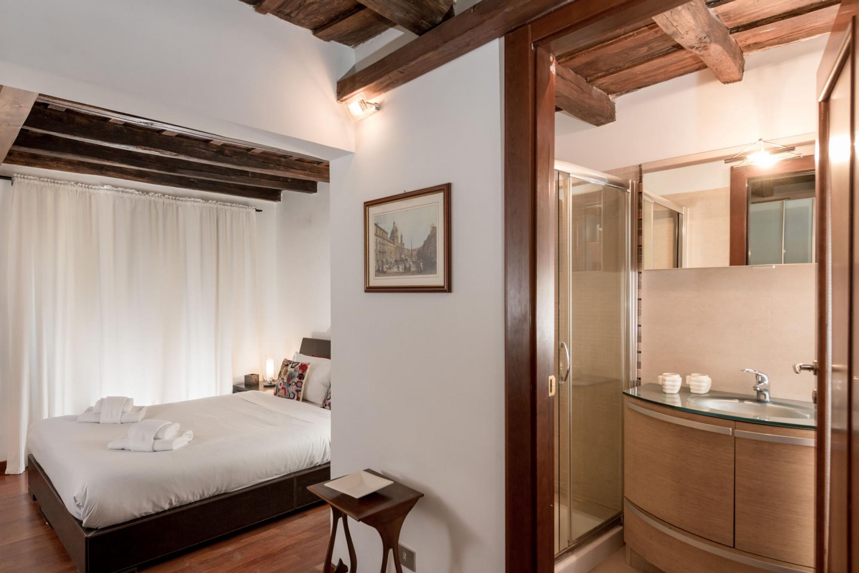 Ein Hotelzimmer mit Bett, Nachttisch und einem Badezimmer mit Duschkabine aus Glas.