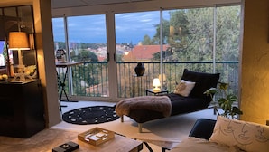 A cozy balcony with a bed, a small table, and a potted plant.