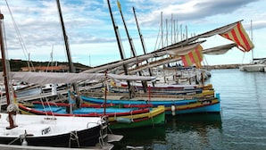 A marina with multiple colorful boats docked, featuring masts and rigging.