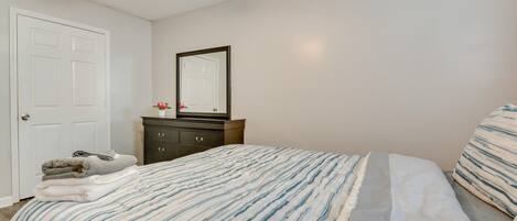 A bedroom with a bed, a dresser, a mirror, and a ceiling fan.