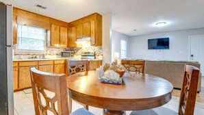 Una cocina con armarios de madera, microondas y una mesa de comedor con sillas.