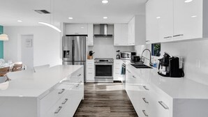 Una cocina moderna con muebles blancos, electrodomésticos de acero inoxidable y una isla central.