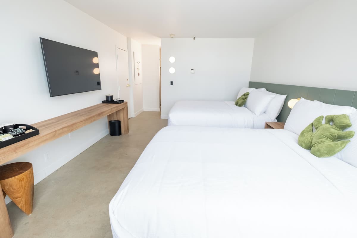 Habitación de hotel con una cama grande, una mesita de noche, un espejo y un televisor instalado en la pared.