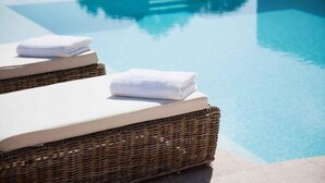 A poolside area with wicker lounge chairs and white towels.