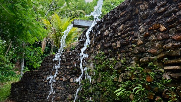 Un mur de pierre avec une cascade qui dévale.