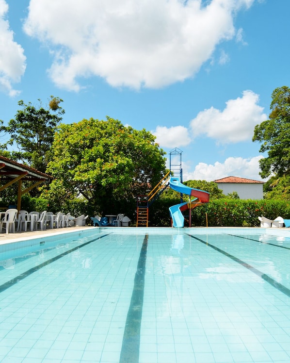 Piscina com escorregador e área de estar coberta.