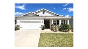 A single-story house with a garage, a front lawn, and a small garden area. - Delightful 2 bdrm home in peaceful area w/parking (ZEPHYRHILLS)