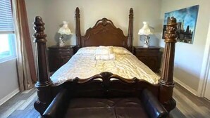 A four-poster bed with a dark wooden frame and a patterned bedspread. There are two bedside tables with lamps on either side of the bed. - Delightful 2 bdrm home in peaceful area w/parking (ZEPHYRHILLS)