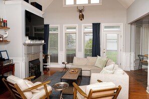 A living room with a fireplace, a mounted deer head, and a television.