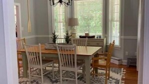 Un comedor con una mesa y sillas de madera, una araña y un tapete estampado.