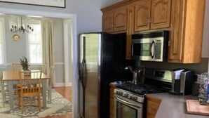 Una cocina con armarios de madera, un refrigerador, una estufa y un microondas.