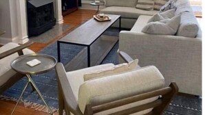 Una sala de estar moderna con chimenea, un televisor de pantalla plana montado encima, un conjunto de sofá, una mesa de centro y una pequeña mesita auxiliar.