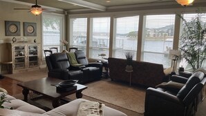 Uma sala de estar espaçosa com vista para a água, uma lareira e um espaço de jantar com mesa e cadeiras.