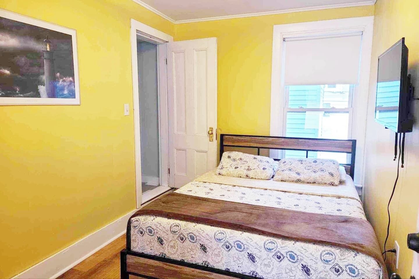Una camera da letto con un letto, una porta, una finestra e una TV a parete.