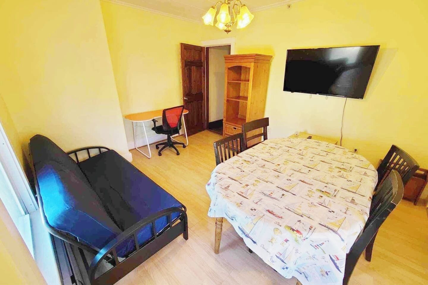 Una habitación con una cama, un escritorio, una silla, un televisor y un armario.