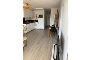 Open-plan living space with kitchen, dining area, and TV.