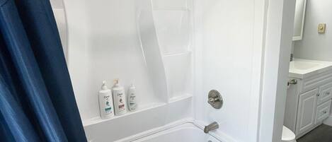 A modern bathroom with a white bathtub, a shower, and a vanity with a mirror.