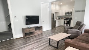 A modern living room with a flat-screen TV, a sofa, and a coffee table. - Triple Play Apt 2 - All Star Baseball Rentals (Oneonta)