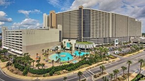A large hotel with multiple floors, a central courtyard with a swimming pool, and a parking area. - “Just Breathe”It’s all about the view & location! Sleeps 7.  (Panama City Beach)