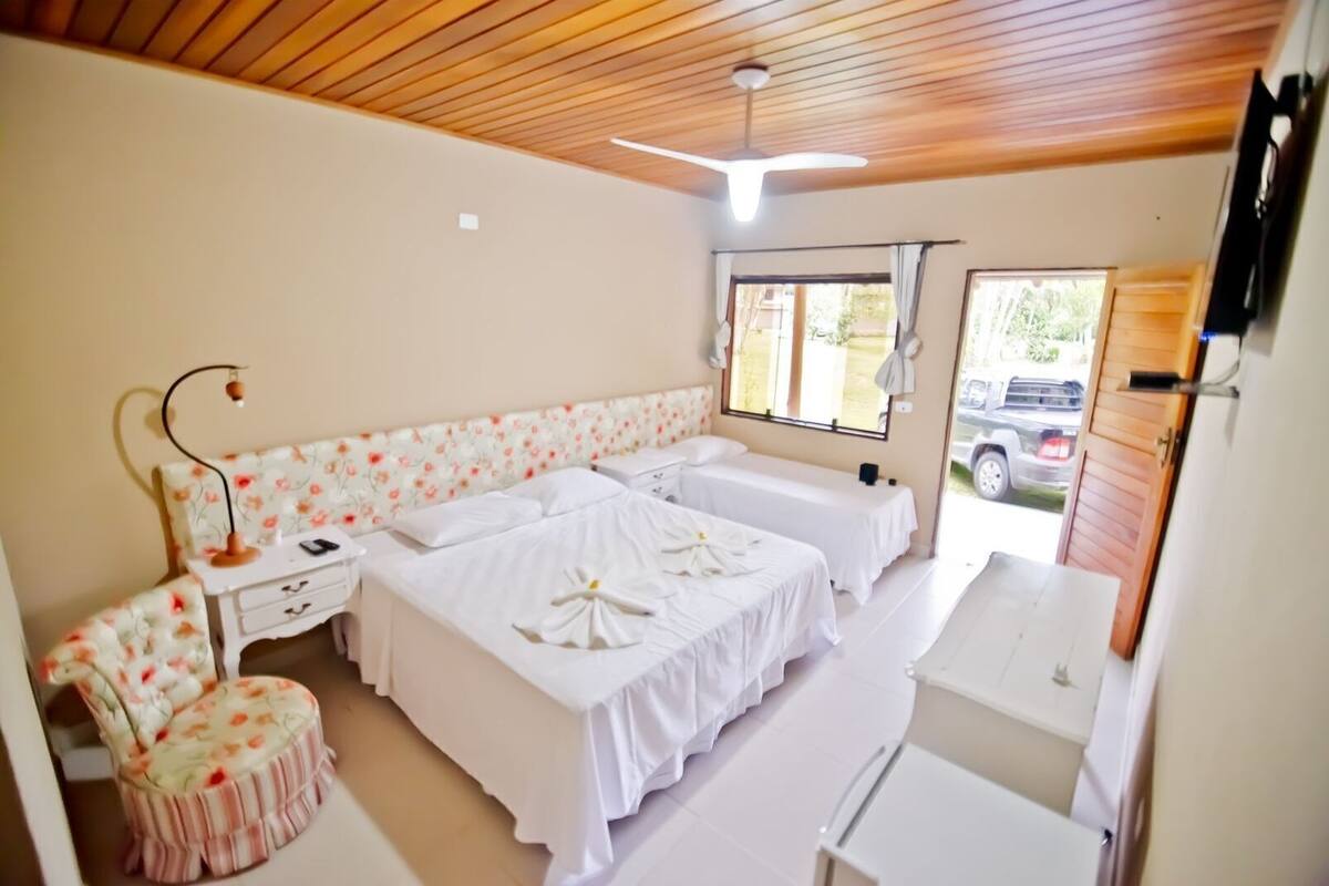 Habitación con dos camas, un escritorio, una silla, un ventilador de techo y una ventana con vistas al exterior.