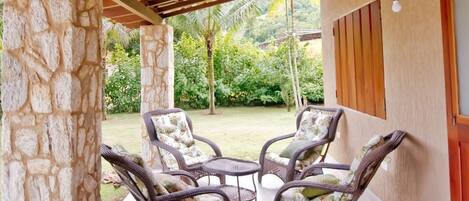 A covered patio area with wicker furniture and a stone pillar.