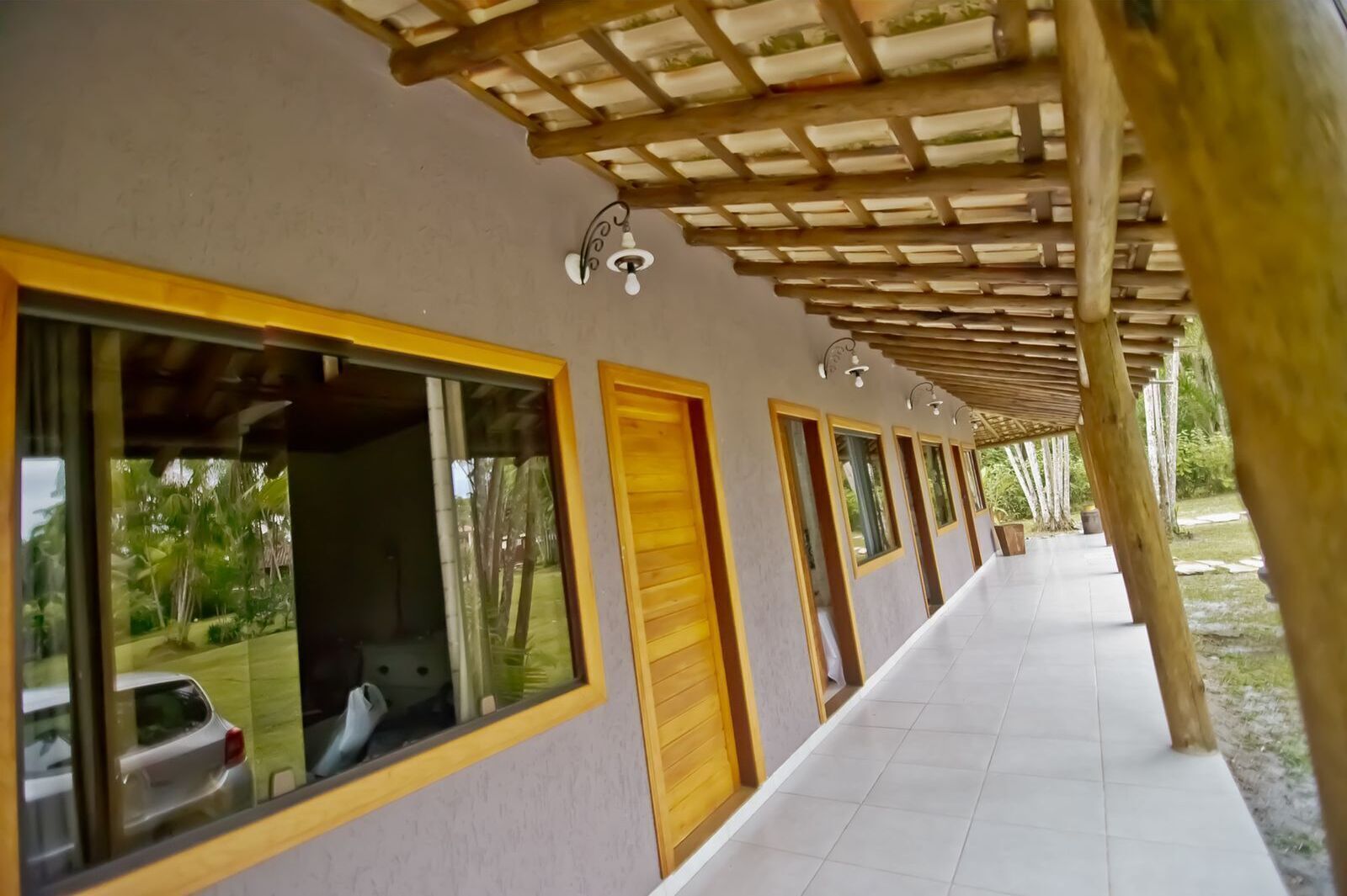 Un pasillo con ventanas amplias, puertas de madera y suelo de baldosas.
